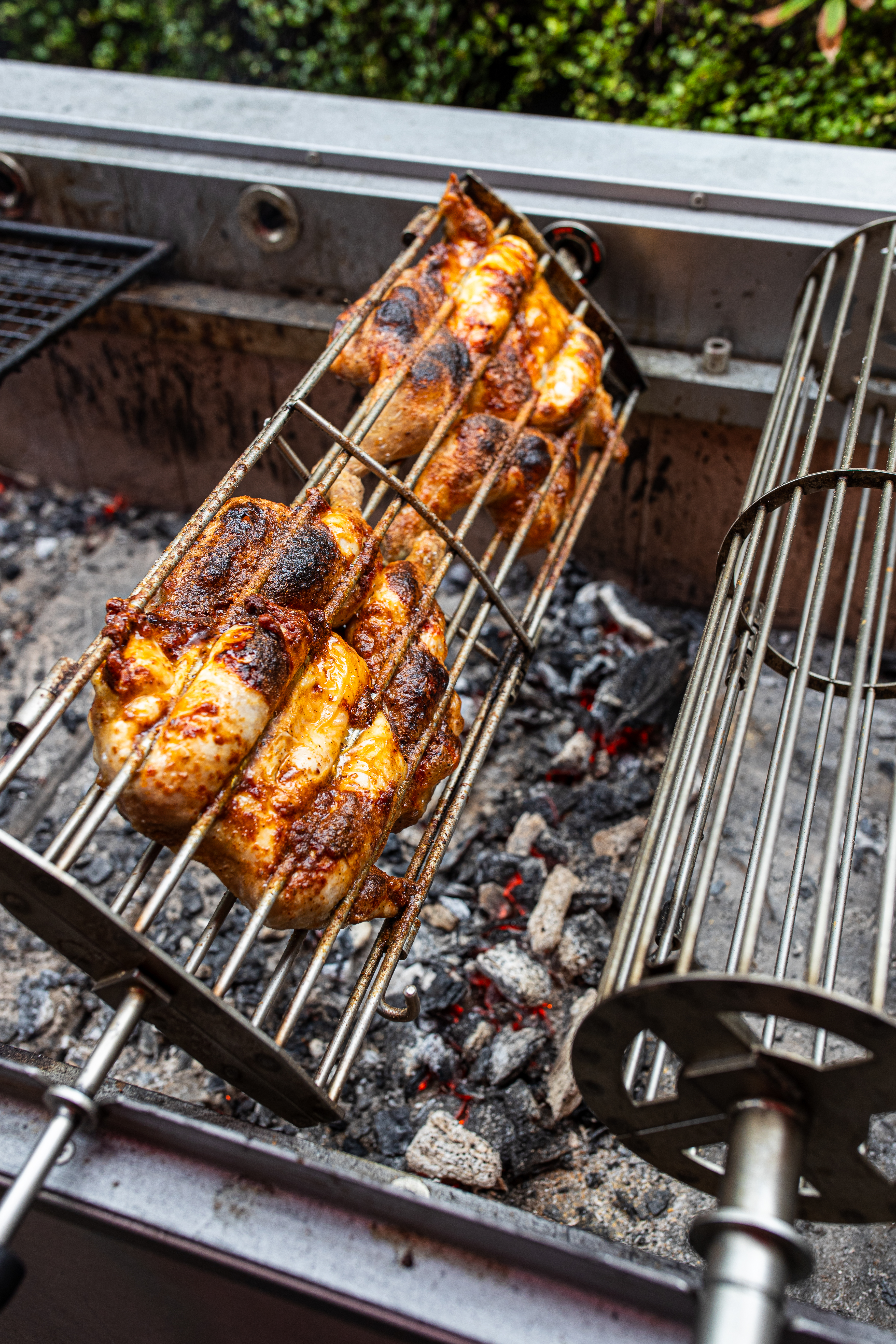 Roasted chickens on a rotisserie over charcoal.
