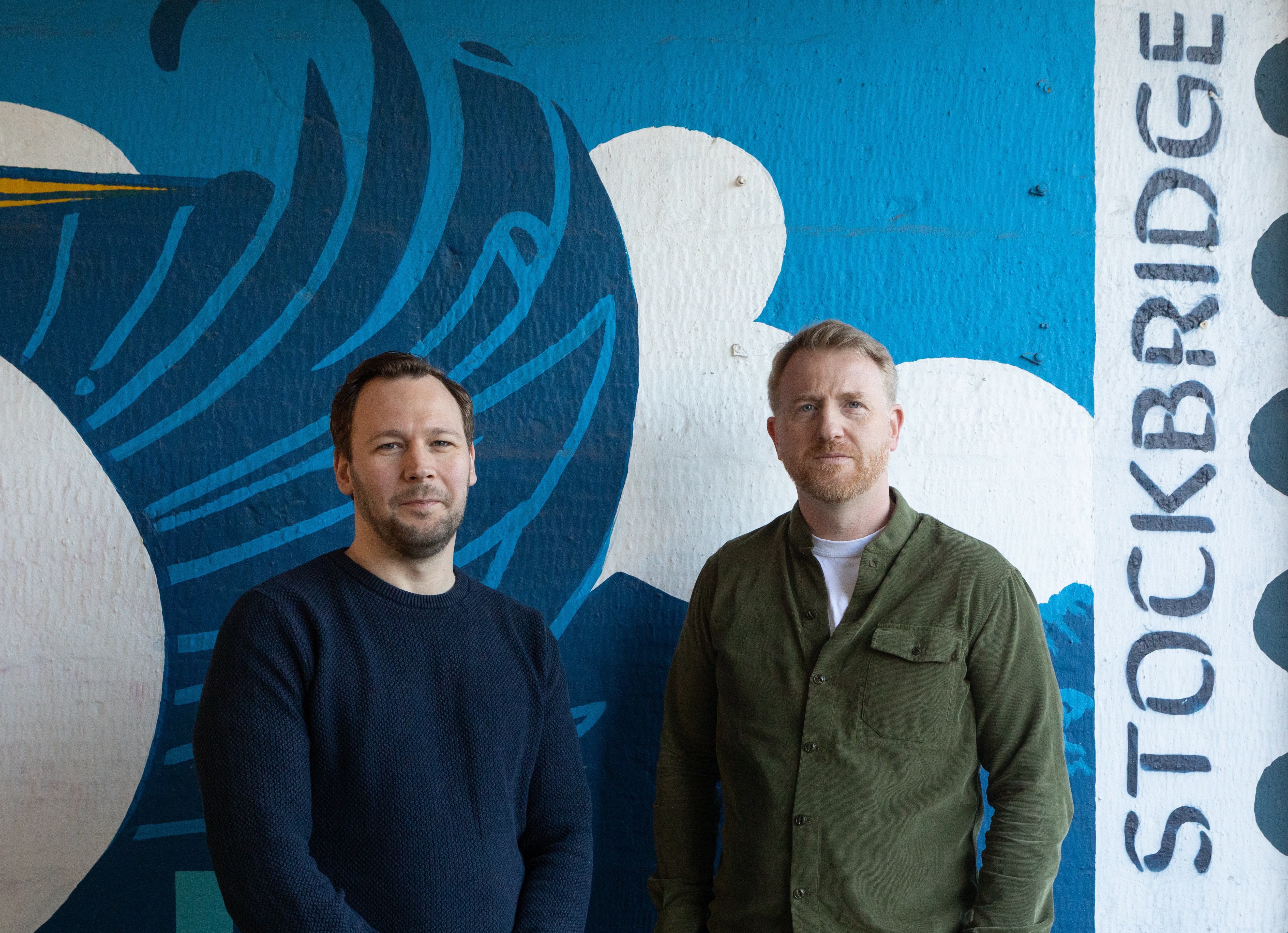 Scott Smith and John Howard in front of a mural.