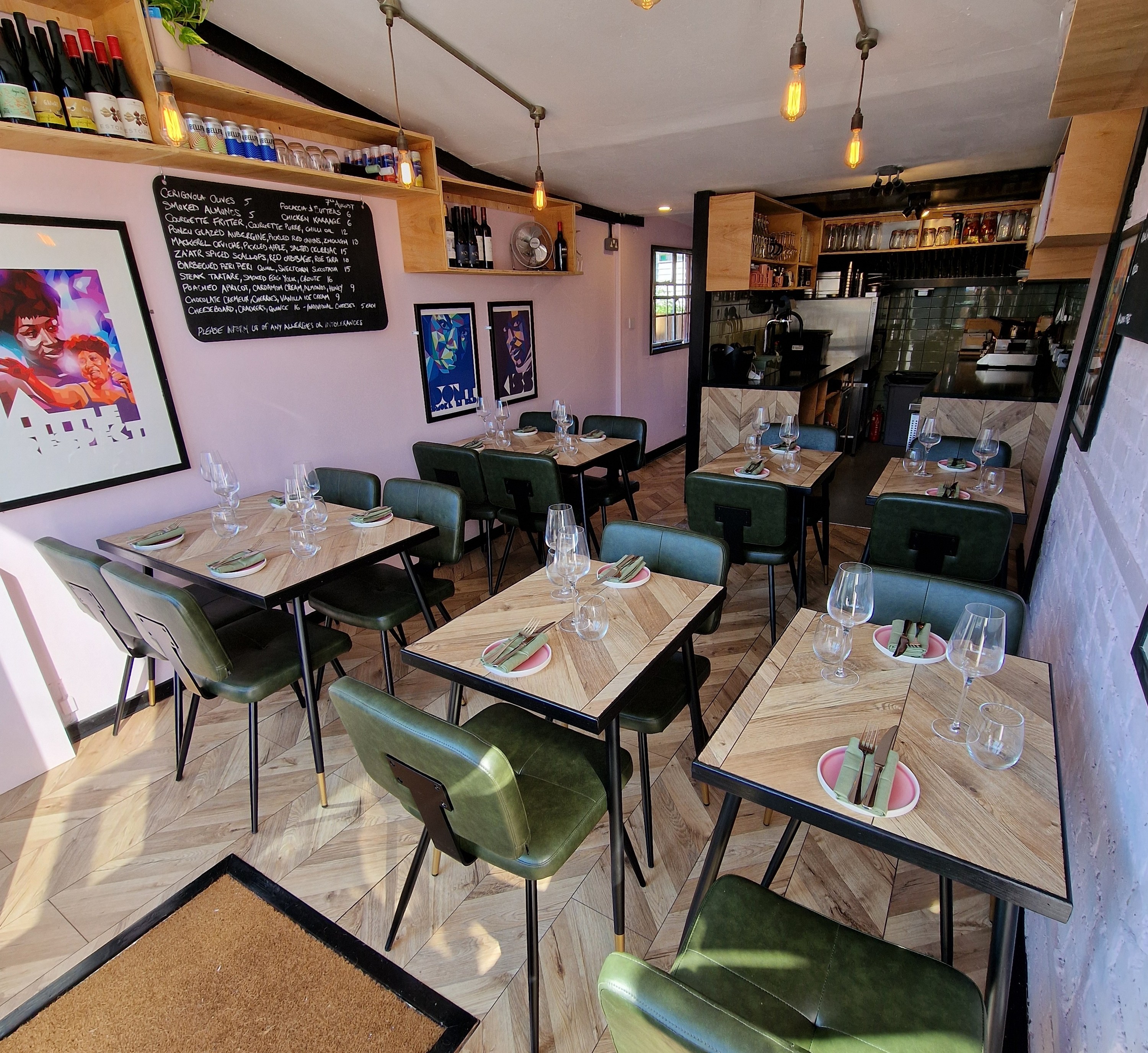 Interior view of a restaurant with several small tables and green chairs.